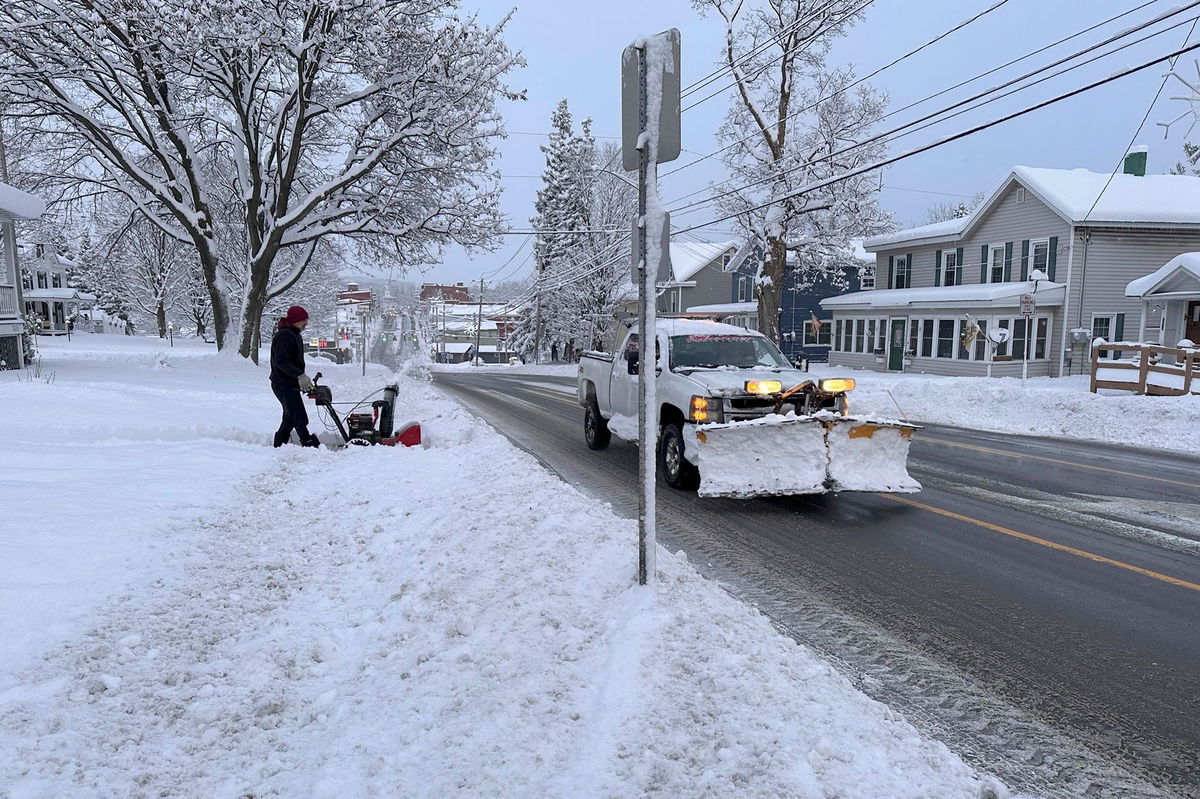 <i>Cara Anna/AP via CNN Newsource</i><br/>A person clears the snow from the sidewalk in Lowville