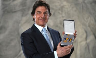 Tom Cruise posing with the Distinguished Public Service Award he received on December 17 from The United States Secretary of the Navy Carlos Del Toro in London.