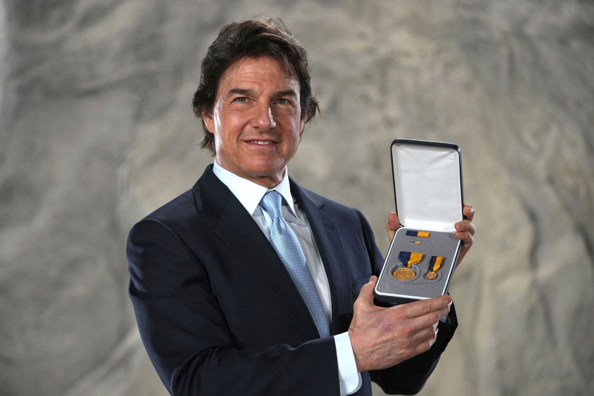 <i>Kin Cheung/AP via CNN Newsource</i><br/>Tom Cruise posing with the Distinguished Public Service Award he received on December 17 from The United States Secretary of the Navy Carlos Del Toro in London.