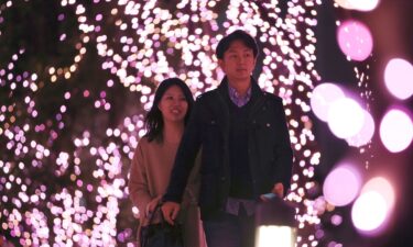 A couple walks through Christmas lights at a shopping area in Tokyo.