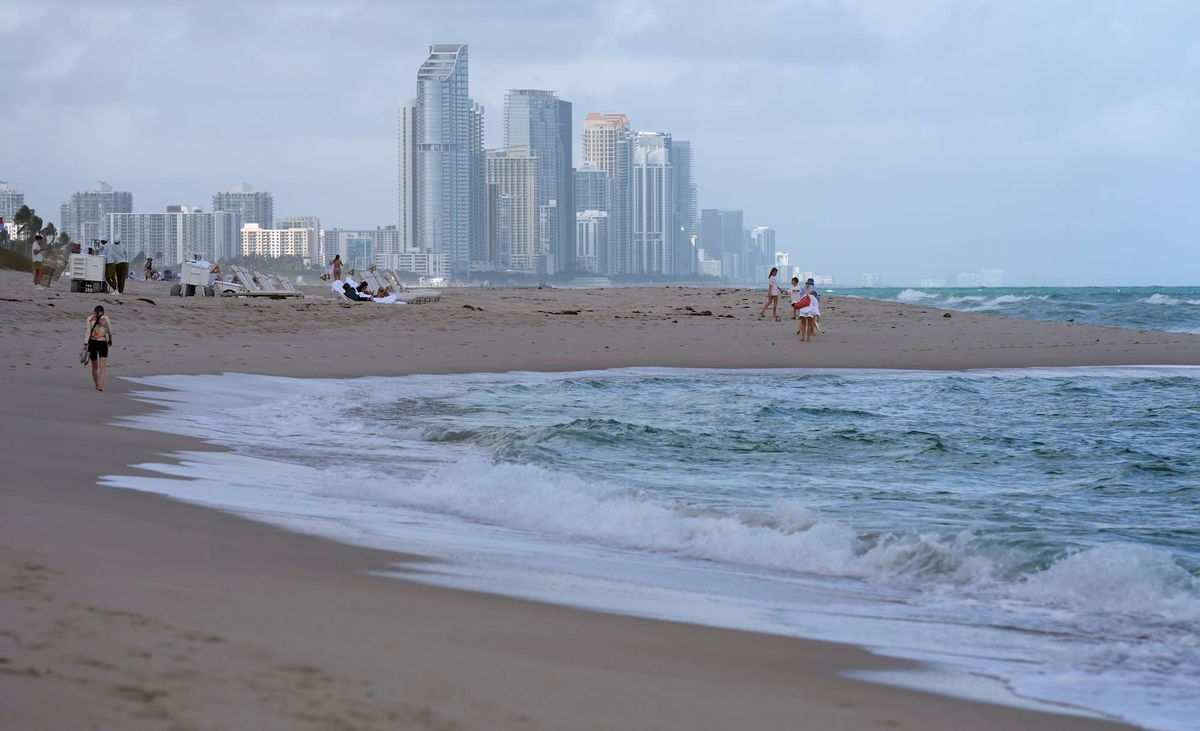 <i>Lynne Sladky/AP via CNN Newsource</i><br/>People walk against the backdrop of the skyline of Sunny Isles Beach