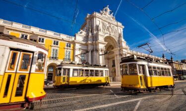 Lisbon's traditional trams pass in front of the Rua Augusta Arch.