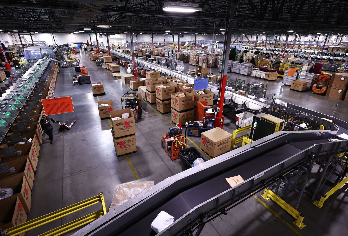 <i>Mario Tama/Getty Images via CNN Newsource</i><br/>US Postal Service employees work inside the Los Angeles Mail Processing & Distribution Center on December 3. The facility is currently processing 1 million packages per day.