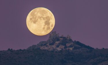 The cold moon sets behind Rocca Calascio castle and village in Calascio