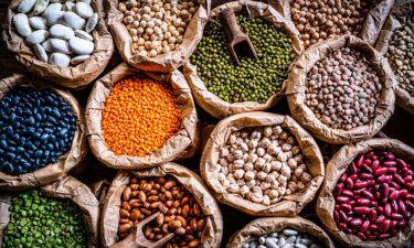 Food Backgrounds: overhead view of several sacks filled with a large variety of dried beans and legumes. The composition includes green