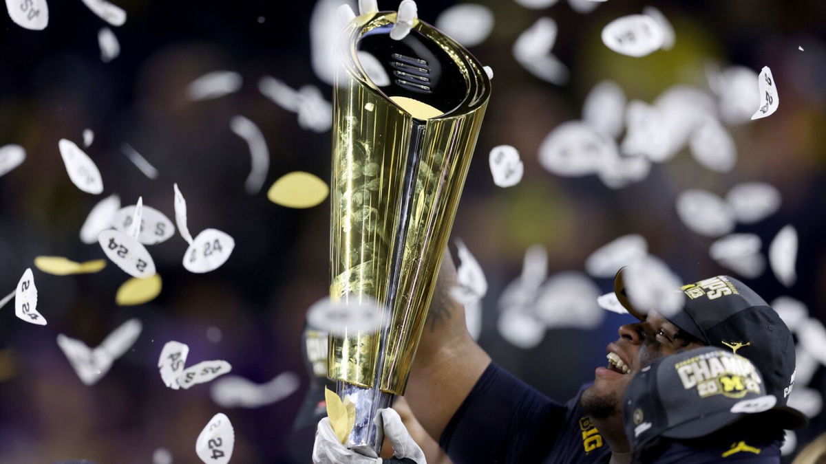 <i>Maddie Meyer/Getty Images via CNN Newsource</i><br/>A player with the Michigan Wolverines raises the College Football Playoff National Championship Trophy after the Wolverines defeated the Washington Huskies in January.