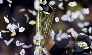 A player with the Michigan Wolverines raises the College Football Playoff National Championship Trophy after the Wolverines defeated the Washington Huskies in January.