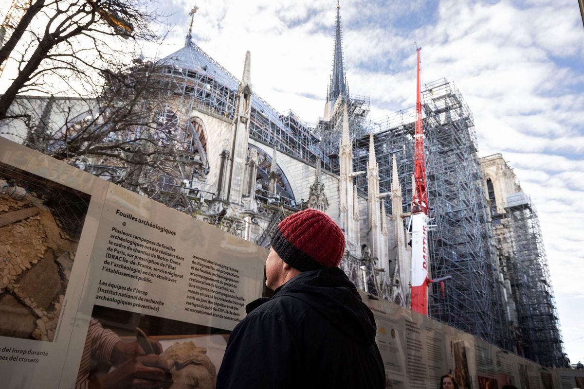 <i>Thomas Hubert/Sipa/AP via CNN Newsource</i><br/>A tourist in front of Notre Dame de Paris Cathedral on the eve of the official reopening five years after the 2019 fire that ravaged the monument.