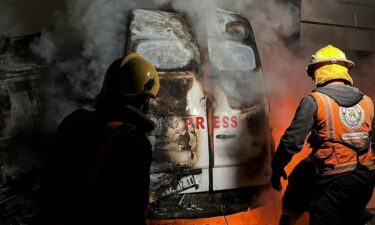 Civil Defense members put out a fire in a broadcast van following an Israeli strike that killed five journalists