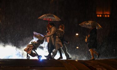 People are seen at a crosswalk on California and Mason street during heavy rain in San Francisco