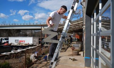 Larry Hopkins of Ananda Hair Studio takes down signage for his store. Hopkins said he had been in the River Arts District location for 13 years before he had to move his store due to flooding by Helene.