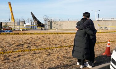 Mourners watch the site of a plane fire from outside of Muan International Airport in Muan