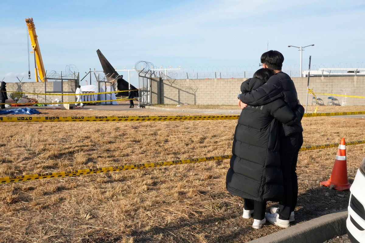 <i>Ahn Young-joon/AP via CNN Newsource</i><br/>Mourners watch the site of a plane fire from outside of Muan International Airport in Muan