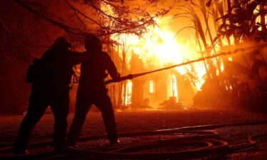 Los Angeles County firefighters spray water on a burning home as the Eaton Fire moved through the area on January 8 in Altadena