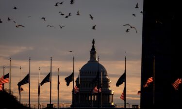 The Dome of the U.S. Capitol Building is visible as flags are lowered to half-staff at the Washington Monument following the death of Jimmy Carter on December 30