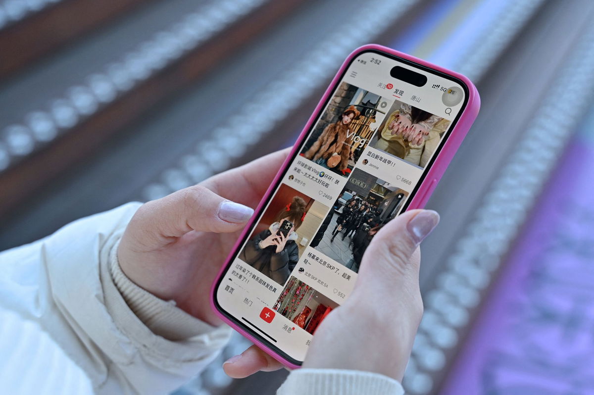 <i>Adek Berry/AFP/Getty Images via CNN Newsource</i><br/>A woman scrolls the Chinese social networking and e-commerce app Xiaohongshu