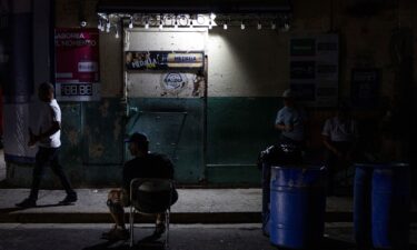 People seat in front of a closed bar in San Juan