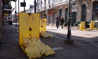 Tourists walk past temporary barriers on Bourbon Street in New Orleans