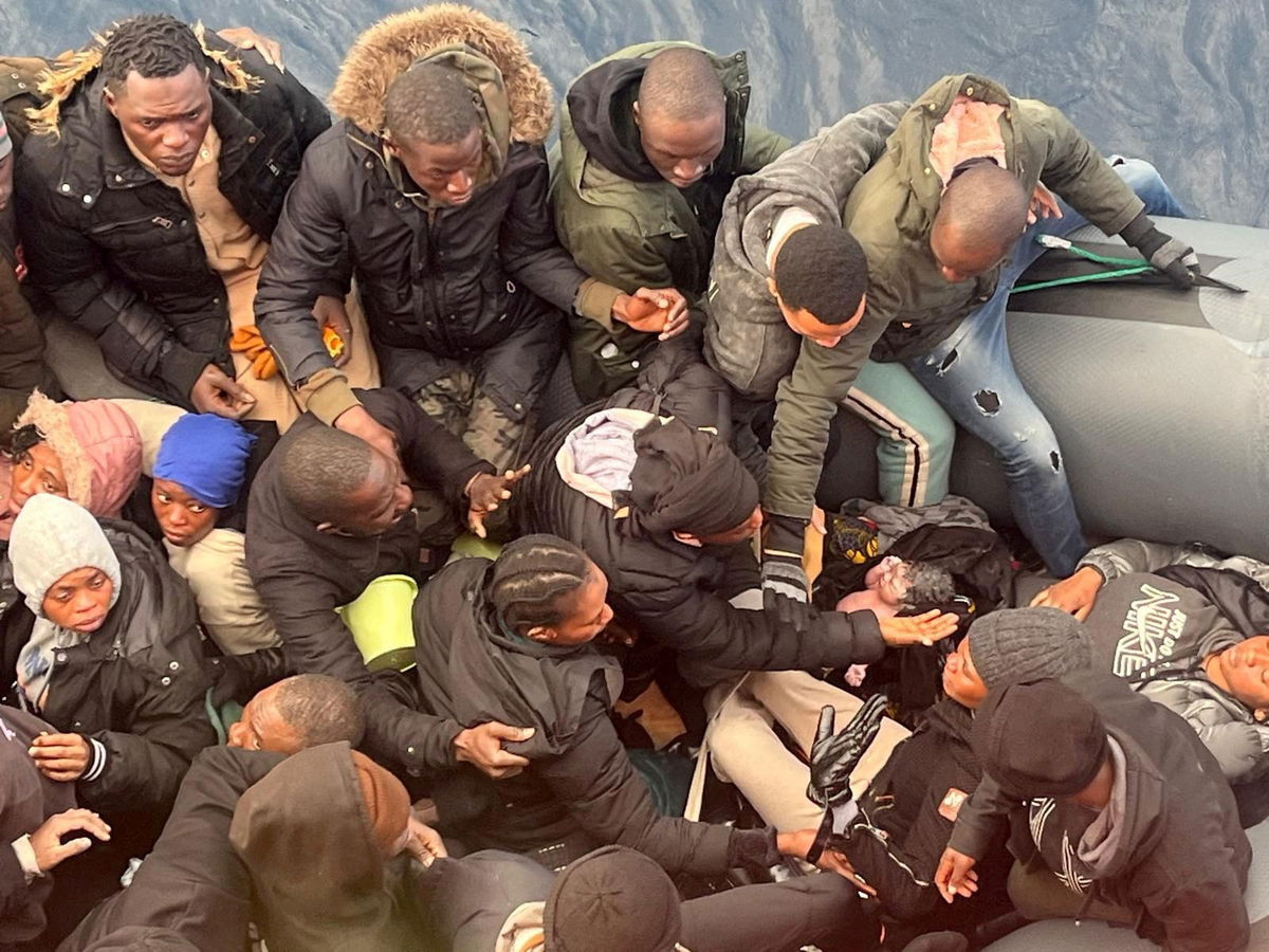 <i>Salvamento Maritimo/Reuters via CNN Newsource</i><br/>A migrant holds a newborn baby as a woman lies inside a rubber boat with other migrants who were rescued off the island off the Canary Island of Lanzarote in Spain