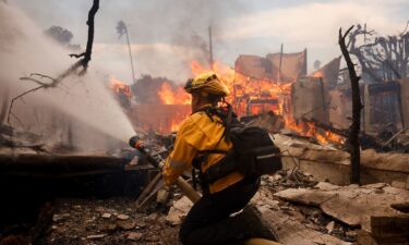 A firefighter battles the Palisades Fire around a burned structure in the Pacific Palisades neighborhood of Los Angeles on January 8.