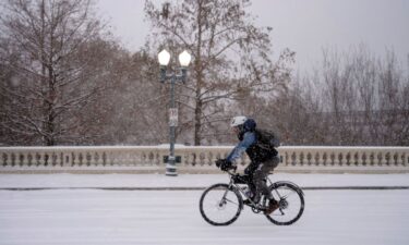 A man bikes along Sabine Street Bridge near downtown as a winter storm brings heavy bands of snow and sleet Tuesday in Houston.