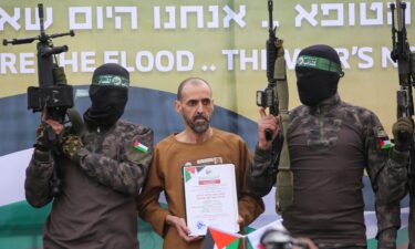 Hamas fighters escort Israeli hostage Eli Sharabi on a stage before handing him over to a Red Cross team in Deir el-Balah