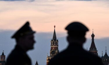 Russian servicemen stand with the Kremlin's Spasskaya tower and Saint Basil's cathedral before the Victory Day military parade rehearsal in central Moscow