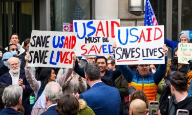 Protesters hold signs during a press conference held by several members of congress in front of the headquarters for United States Agency for International Development (USAID) on February 3 in Washington