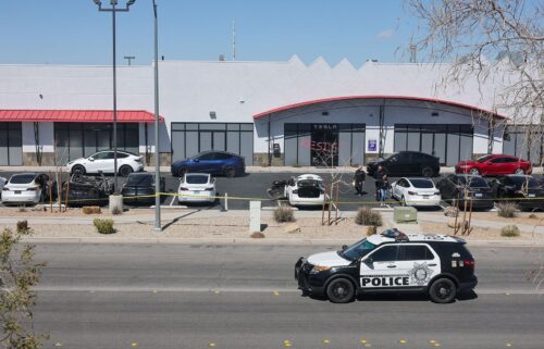 Investigators look over the scene at a Tesla Collision Center after an individual used incendiary devices to set several vehicles on fire on March 18