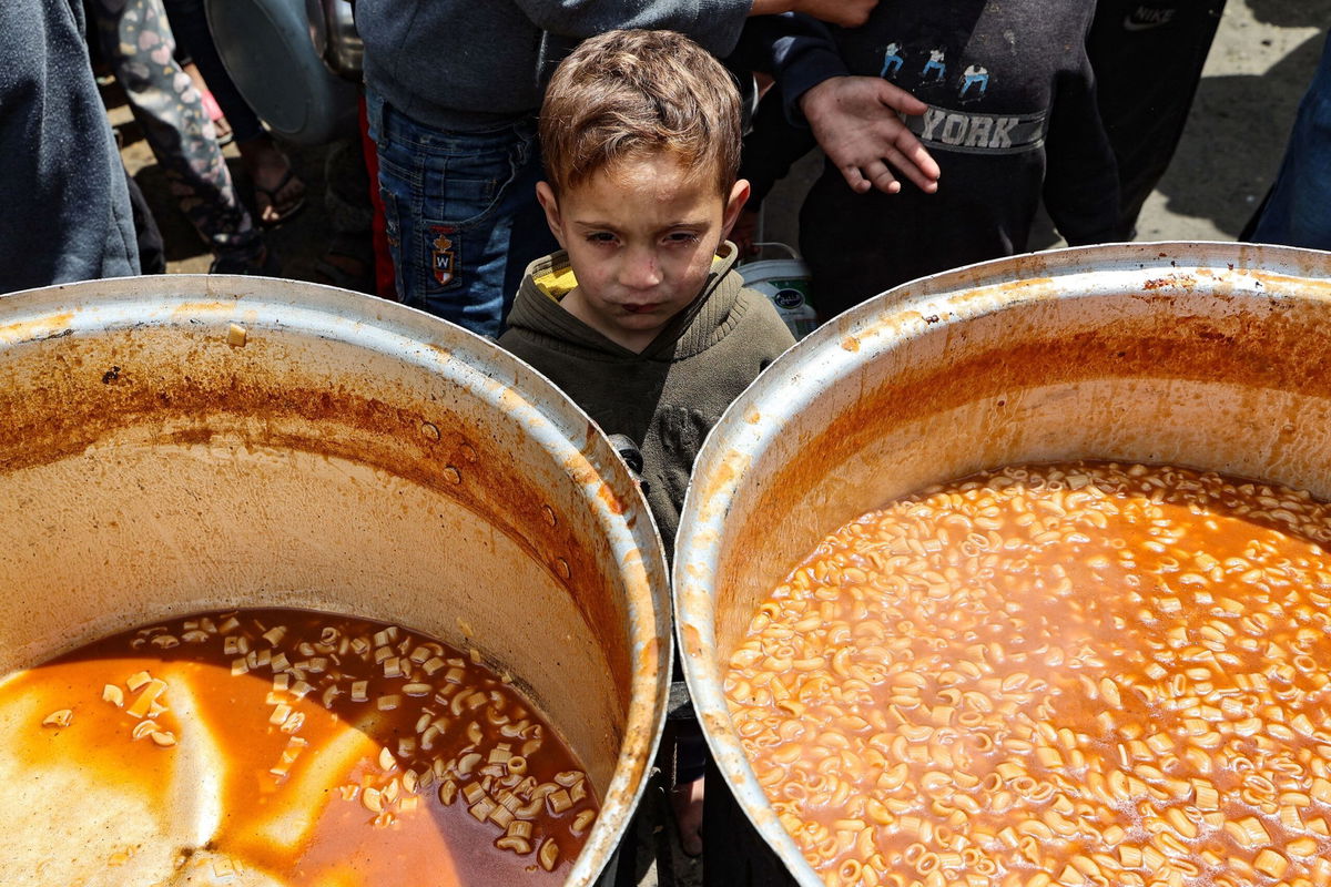<i>Eyad Baba/AFP via Getty Images via CNN Newsource</i><br/>A Palestinian child waits to receive his portion of a hot meal at a free food distribution point at the Nuseirat refugee camp in the central Gaza Strip on April 12.