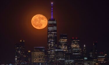 The flower moon rises behind the skyline of lower Manhattan and One World Trade Center in New York City on May 24