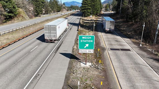 A semi-truck driver passes an open weigh station