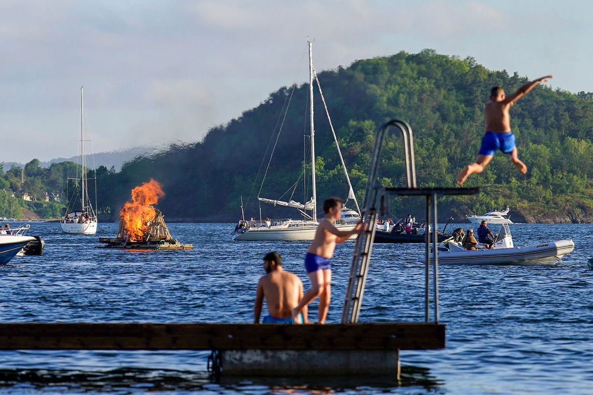 <i>Hakon Mosvold Larsen/NTB/AFP/Getty Images via CNN Newsource</i><br/>A floating bonfire marks midsummer celebrations as people enjoy the water in the Oslo Fjord by Bjorvika in June 2022. After their long