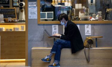 A man uses his laptop outside a coffee shop in Shanghai