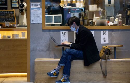 A man uses his laptop outside a coffee shop in Shanghai