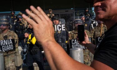 A person holds up their phone in front of the National Guard and police as they confront protesters following three days of clashes with police after a series of immigration raids on June 9 in Los Angeles.