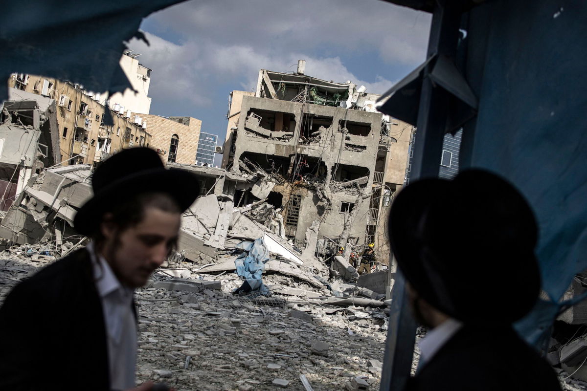 <i>John Wessels/AFP/Getty Images via CNN Newsource</i><br/>Men inspect damage at the site of an Iranian missile strike in Bnei Brak