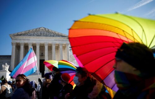 People hold rainbow-colored umbrellas and flags at a demonstration as the US Supreme Court hears arguments over an appeal by President Joe Biden's administration of a lower court's decision upholding a Republican-backed ban in Tennessee on gender-affirming medical care for transgender minors