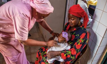 A nurse detects malnutrition in a baby using arm circumference measurement as part of ALIMA’s malnutrition project