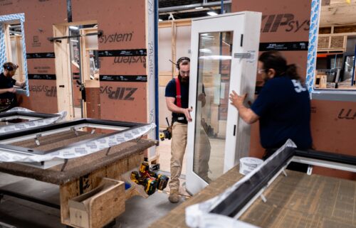 Workers install windows and doors in one Unity home panel.