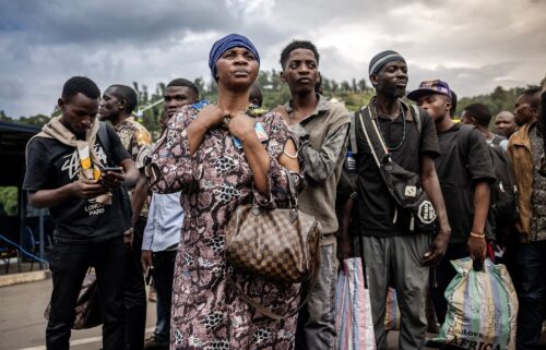 Congolese families displaced by ongoing clashes in eastern Democratic Republic of Congo line up as they wait for Rwandan police and immigration officials to allow them to return to the country