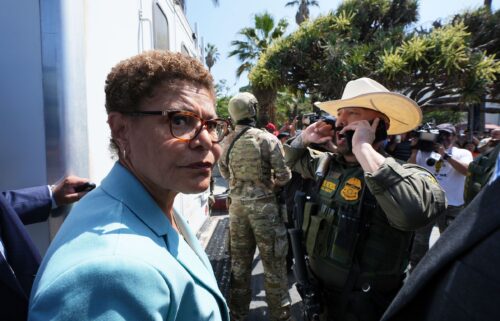 Los Angeles Mayor Karen Bass stands in front of a border patrol federal agent at MacArthur Park on Monday.