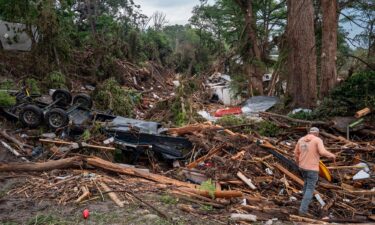 A volunteer walks through debris while assisting with search and rescue efforts on the banks of the Guadalupe River in Center Point