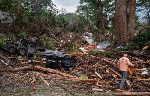 A volunteer walks through debris while assisting with search and rescue efforts on the banks of the Guadalupe River in Center Point