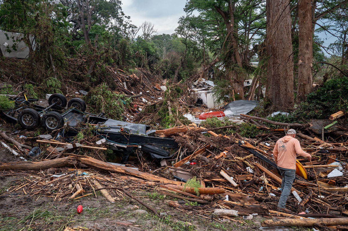 <i>Brandon Bell/Getty Images via CNN Newsource</i><br/>A volunteer walks through debris while assisting with search and rescue efforts on the banks of the Guadalupe River in Center Point