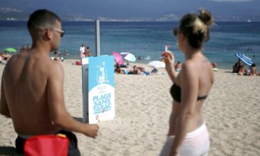 A man and woman smoke cigarettes by a non-smoking beach in Ajaccio