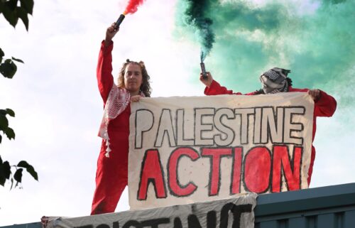Activists hold a banner saying "Palestine Action" while letting off smoke flares in Brandon