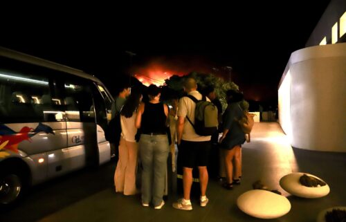 Tourists evacuate a hotel on Crete as wildfires burn.