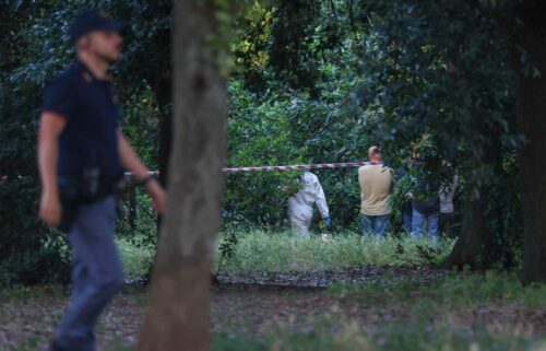 A police officer walks past a sealed-off area where forensic police work at the site of the discovery of the body of an infant and the infant’s mother