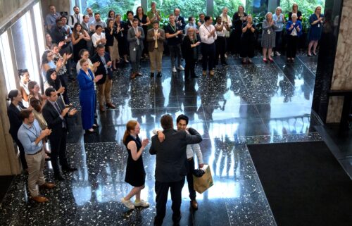 State Department employees applaud as their colleagues walk through the lobby of the State Department headquarters in the Harry S Truman Building